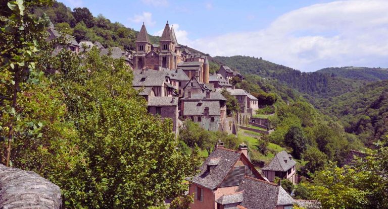 Village médiéval niché dans une vallée verdoyante, evoquant Baume-les-Messieurs dans le Jura