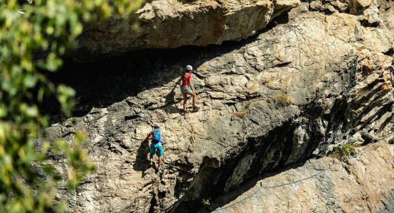 Deux grimpeurs progressant sur une via ferrata le long d'une falaise rocheuse